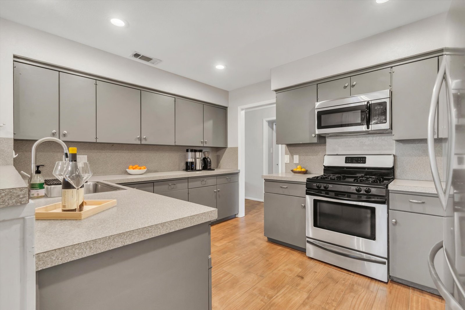 Kitchen showing gas range, stainless microwave, gray cabinets, counter space, and island with dishwasher