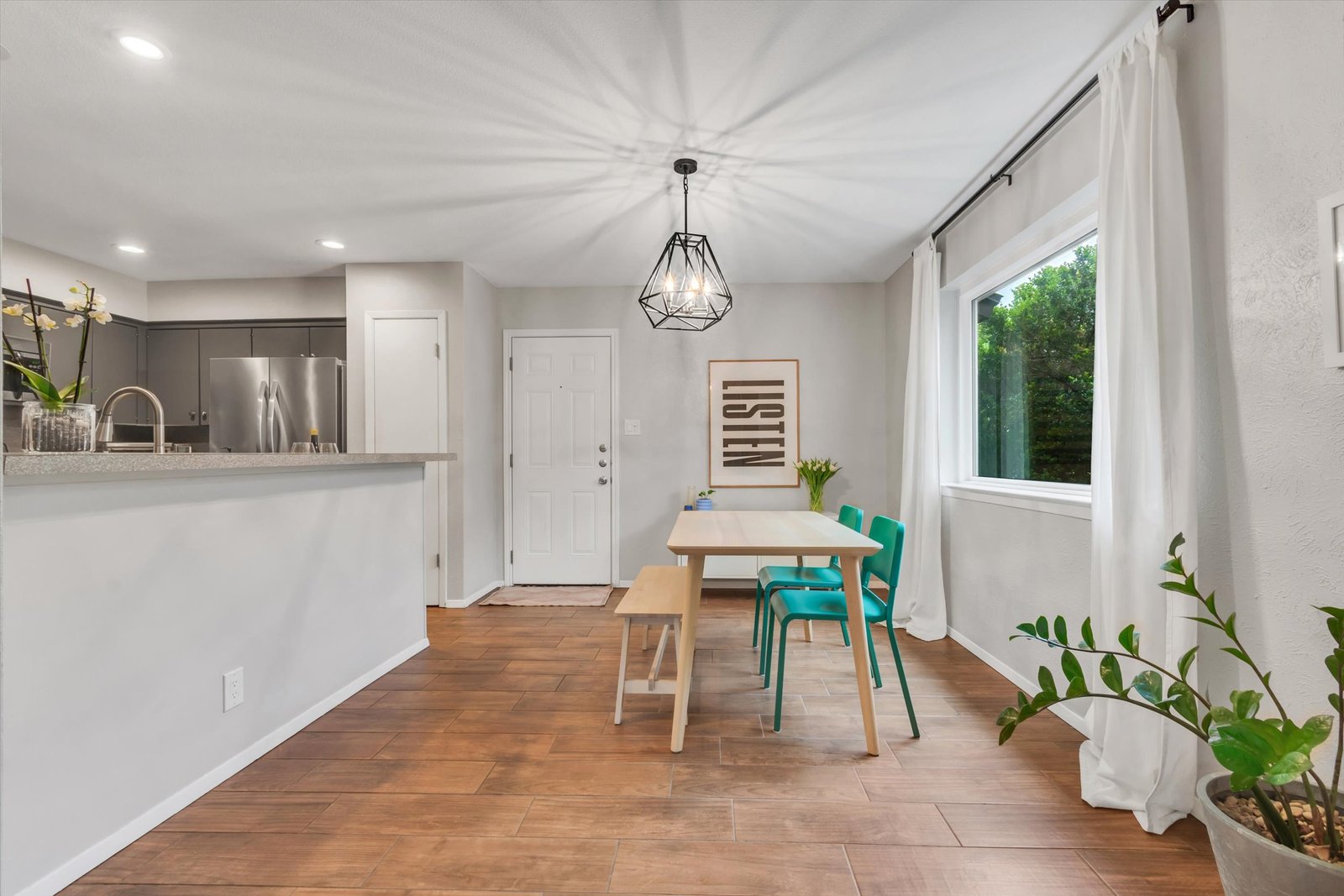 Dining area showing kitchen pass-through with breakfast bar, geometric chandelier, and garage entry door