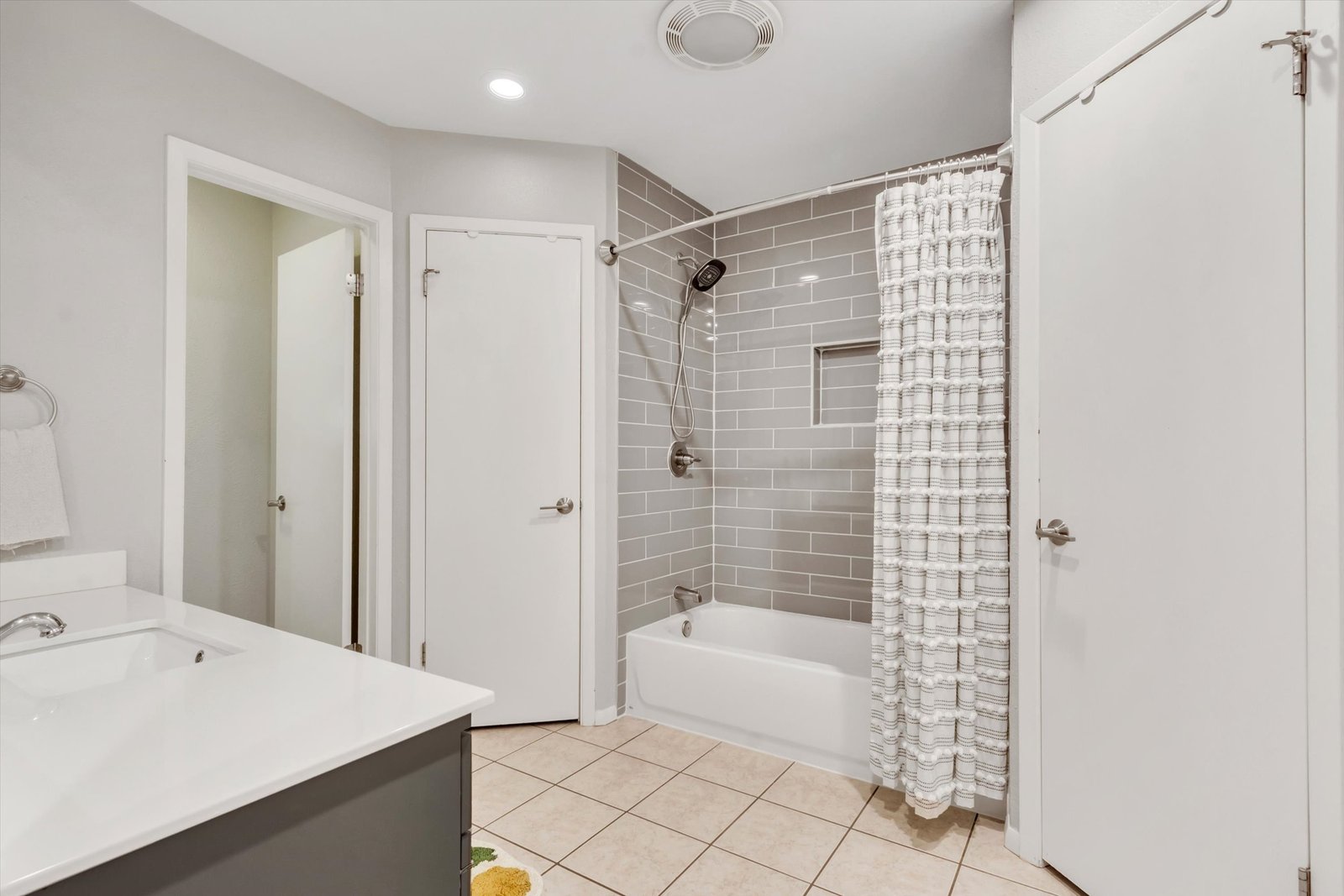 Primary bath alternate angle — tub/shower with subway tile surround, shower curtain, gray vanity with mirror