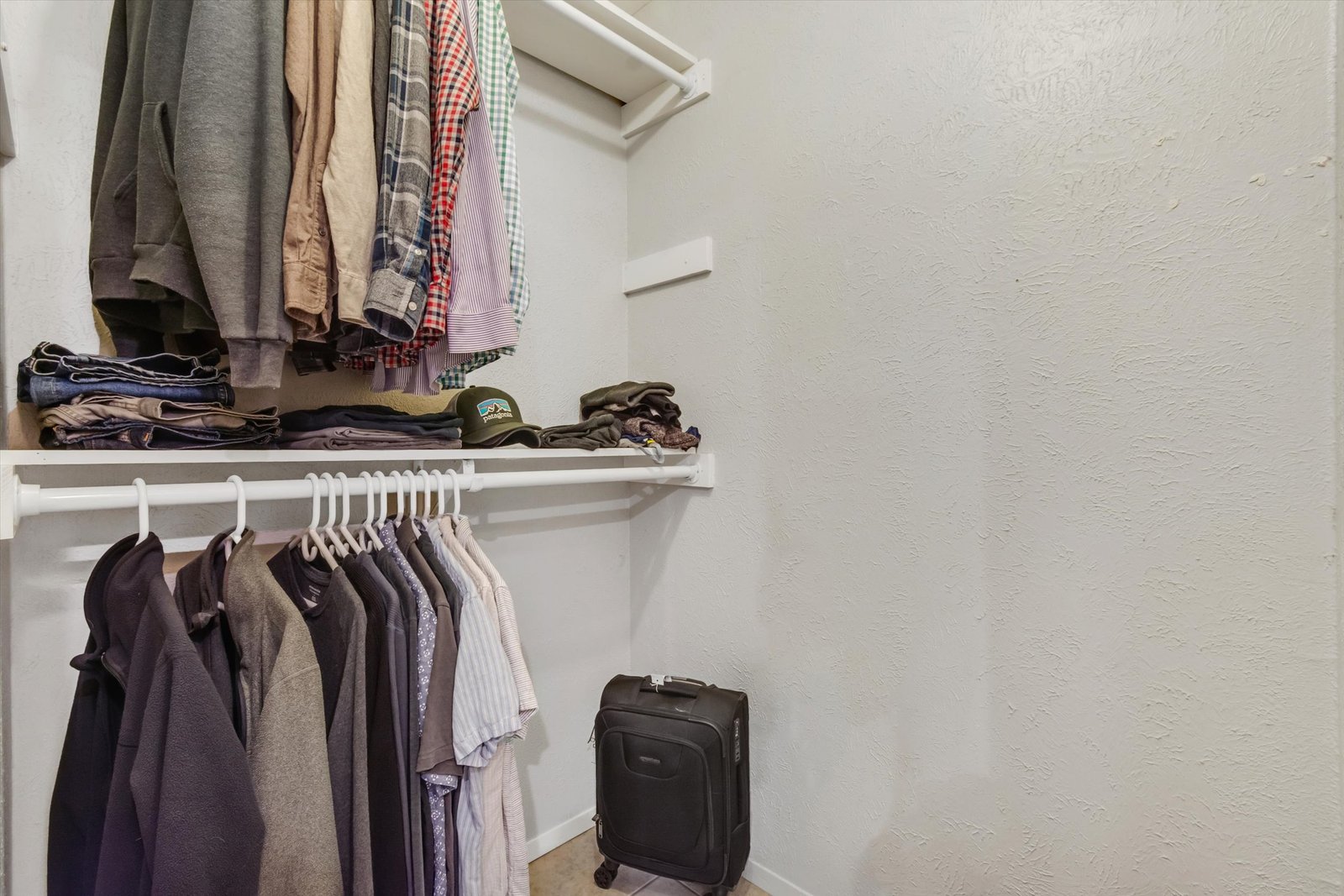 Primary walk-in closet with double hanging rods and shelf storage
