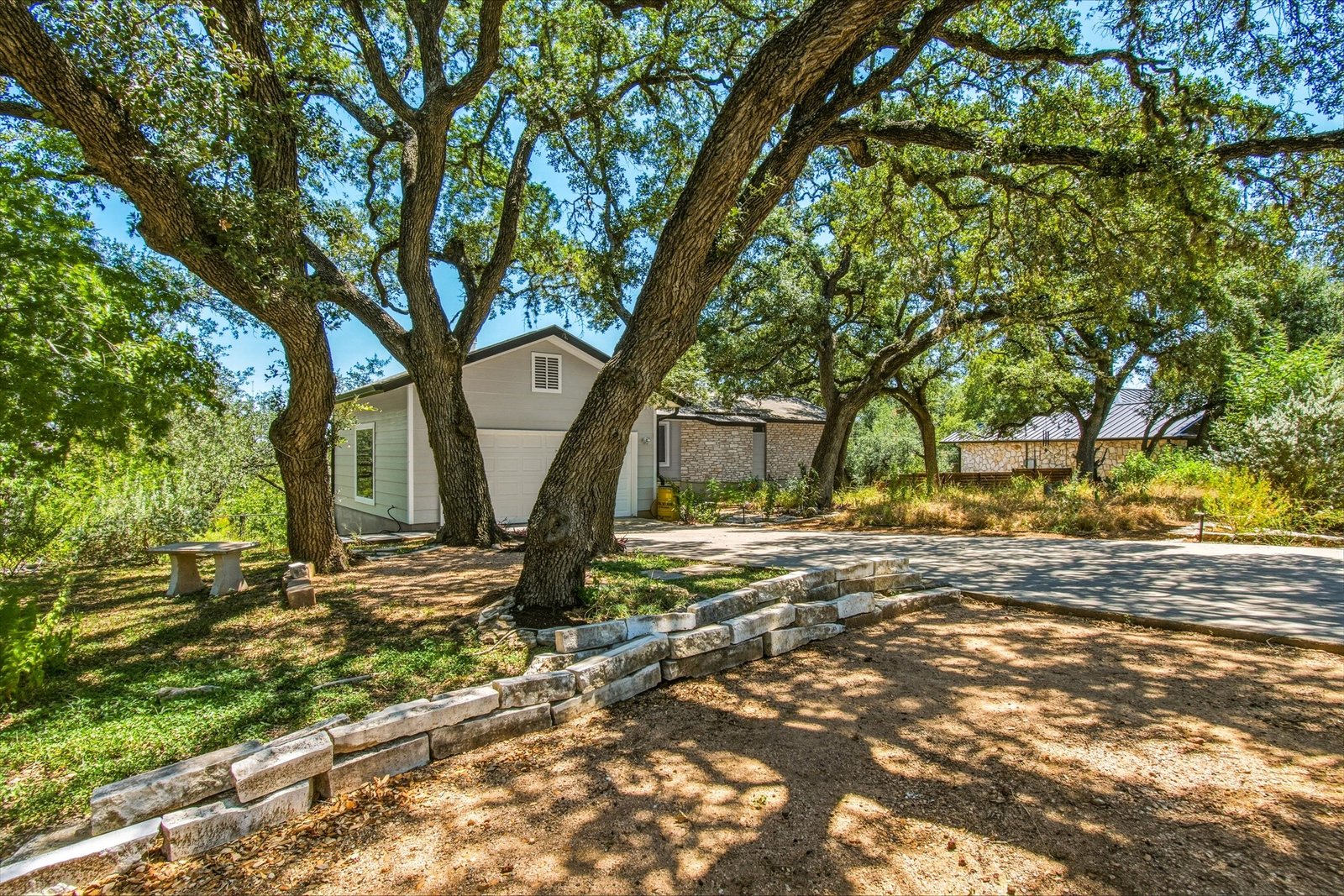 Front exterior with stone terracing and mature live oaks