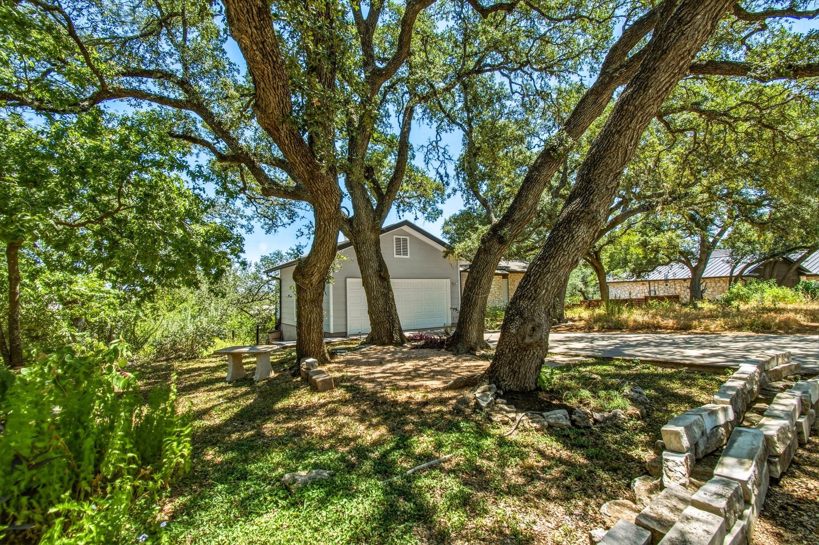 Side-front view of the home and garage shaded by heritage oaks