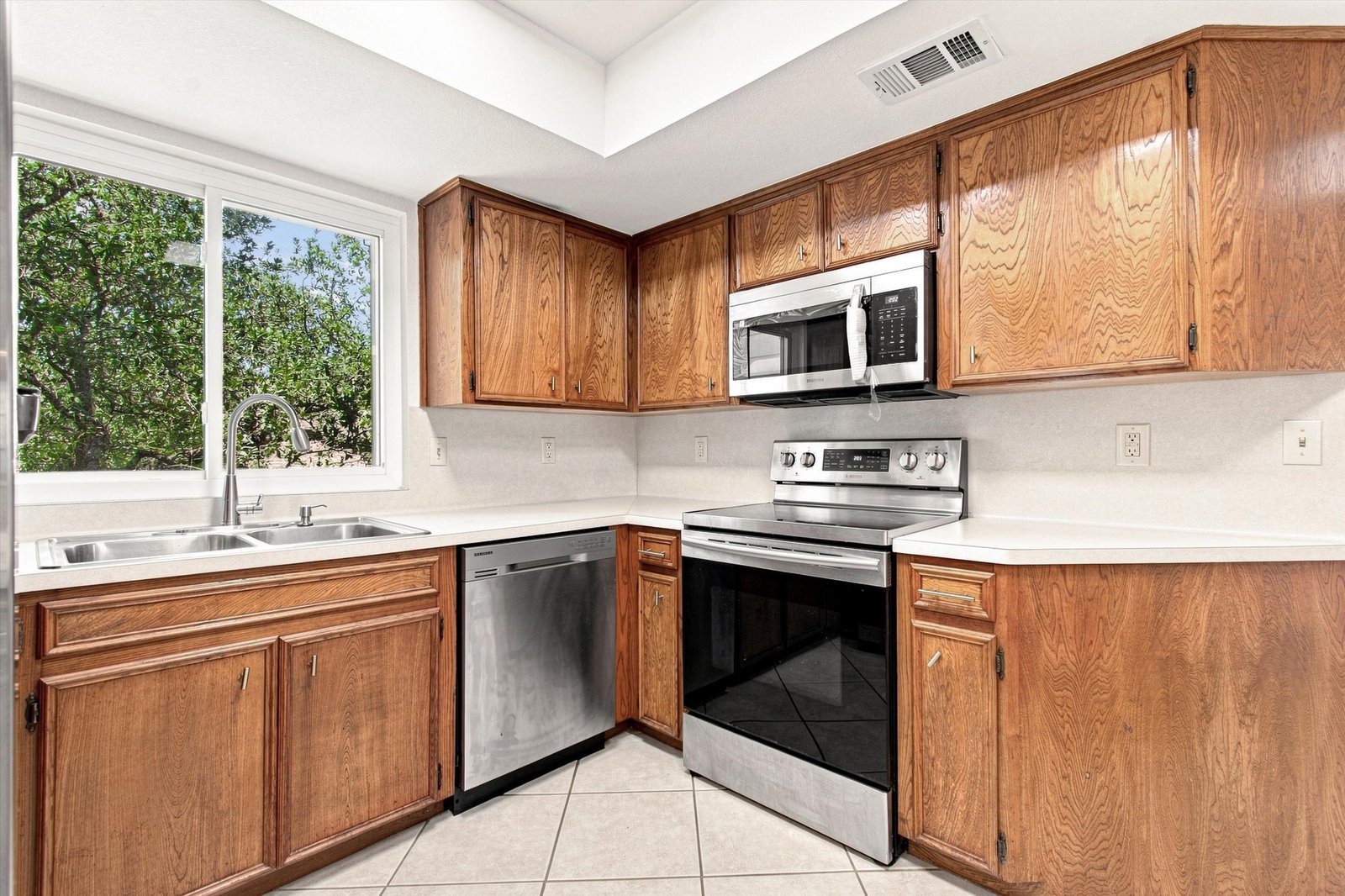 Kitchen with stainless steel range, dishwasher, microwave, and window over the sink