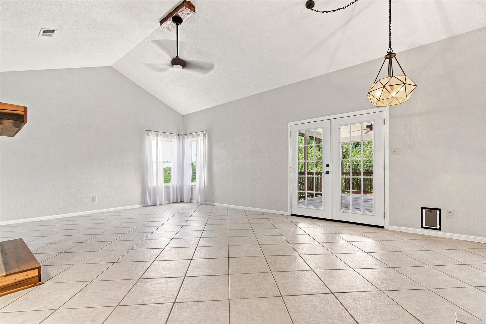 Great room with vaulted ceiling, tile floors, and bay window