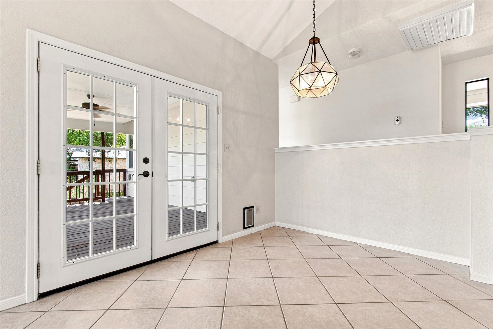 Great room French doors opening to the covered deck under a vaulted ceiling