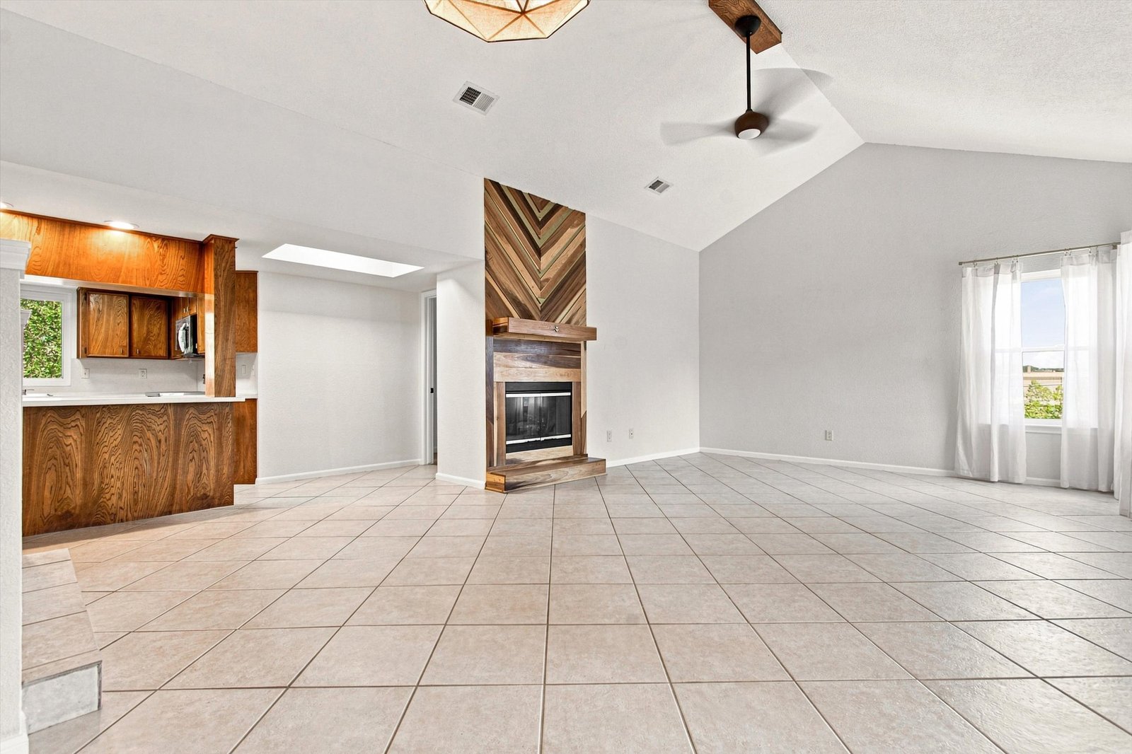 Great room with chevron wood fireplace surround open to the kitchen