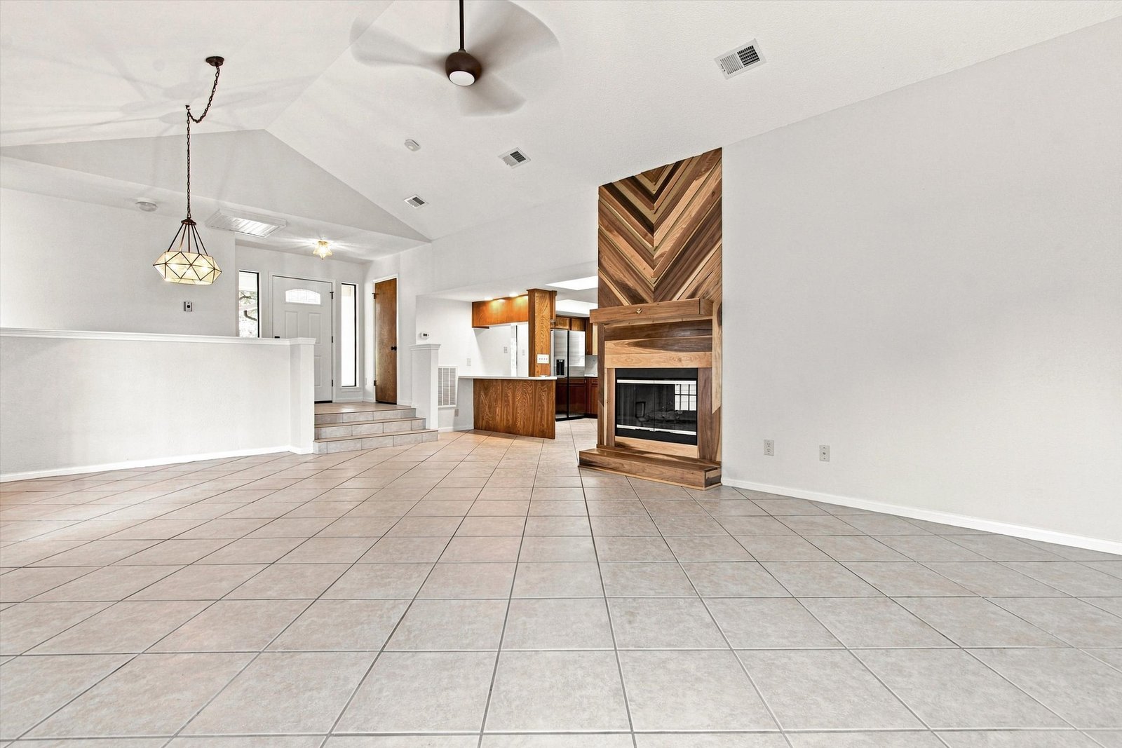 Great room wide view toward the entry with tile floors and fireplace
