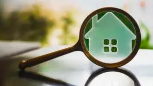 Magnifying glass focused on a model house — pre-listing inspection and appraisal